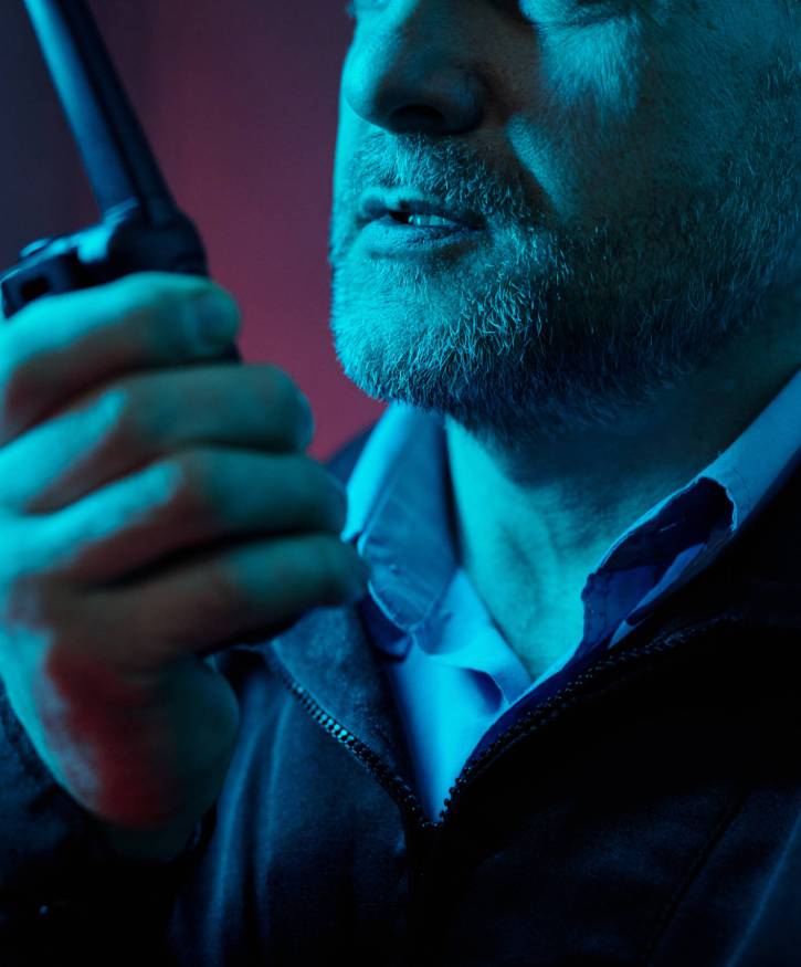 Cropped shot of mature male guard speaking to colleague in walkie-talkie while notifying situation during night duty watch